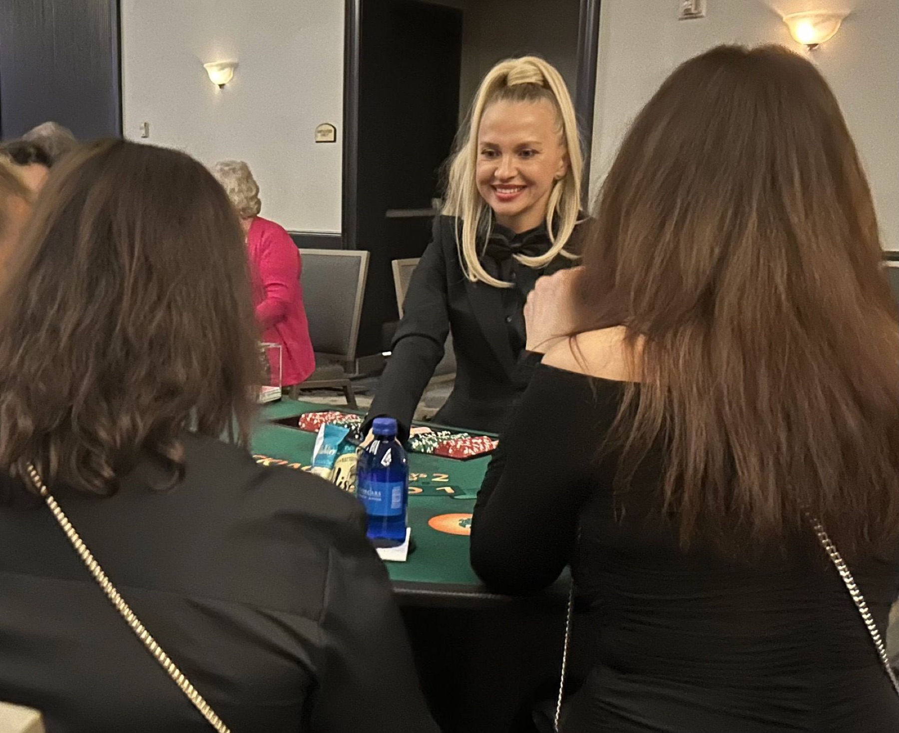 A dealer smiling with guests at a blackjack table
