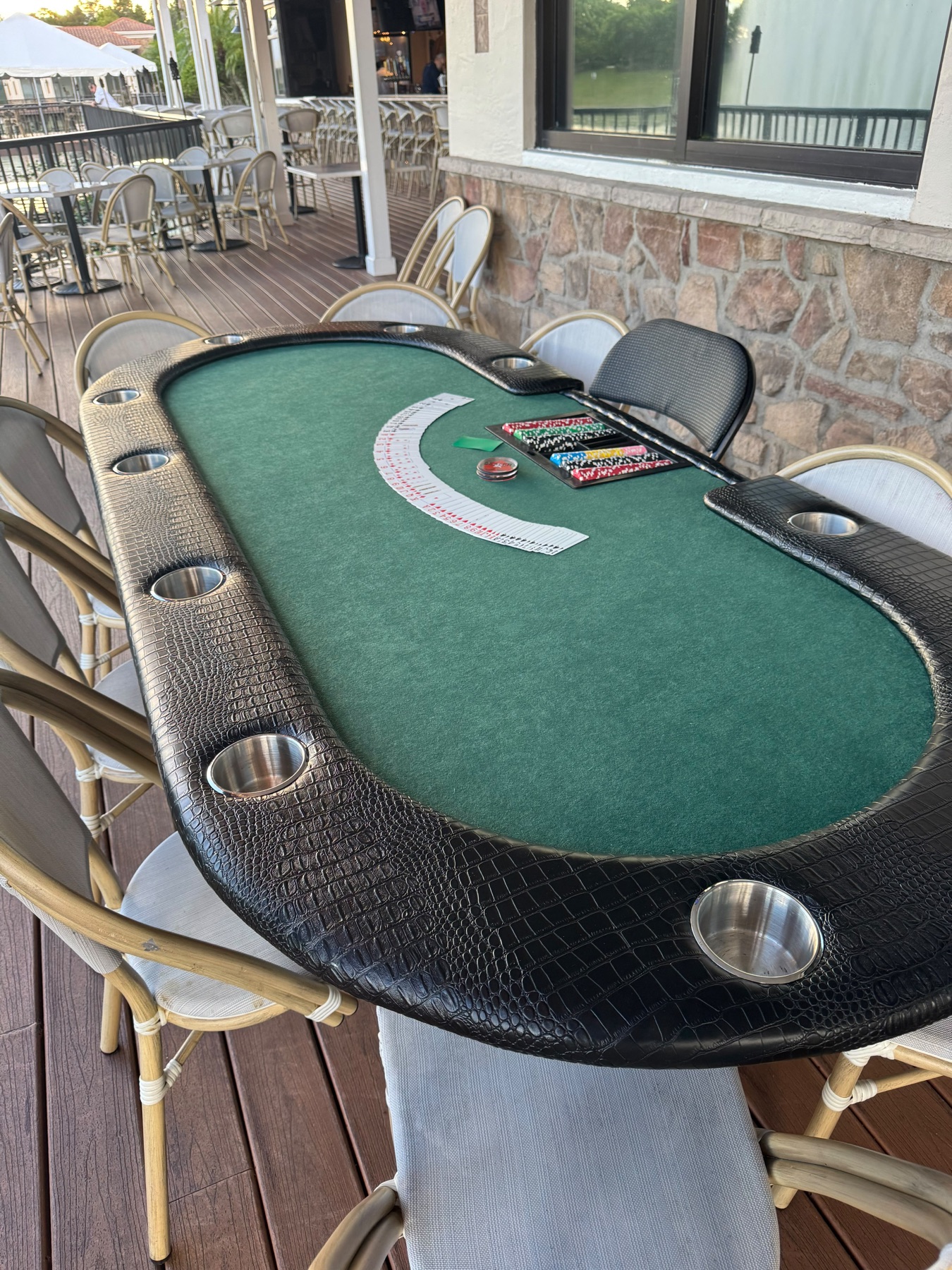Full-size casino poker table set up on a covered patio for a private party